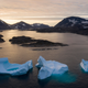 icebergs float away as the sun rises near Kulusuk, Greenland.